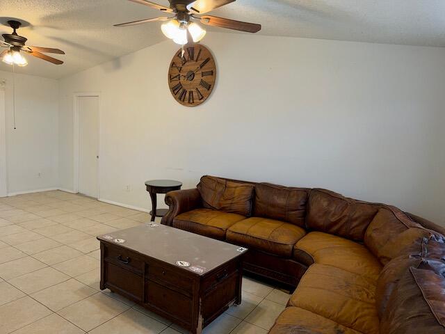 tiled living room with vaulted ceiling and ceiling fan