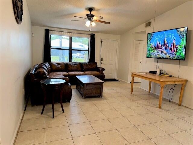 living room featuring ceiling fan, lofted ceiling, and light tile patterned floors