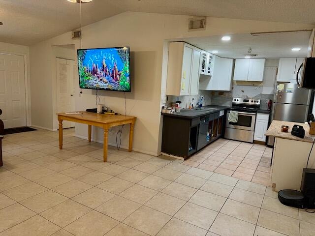 kitchen featuring lofted ceiling, stainless steel appliances, sink, light tile patterned floors, and white cabinetry