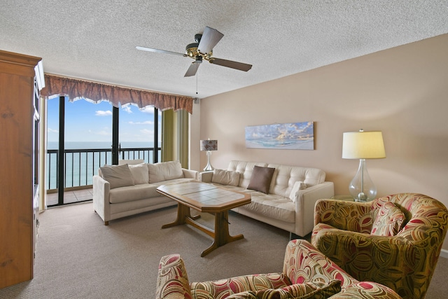 living room with ceiling fan, carpet floors, a textured ceiling, and a water view