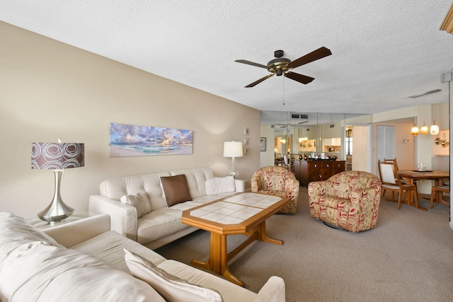 carpeted living room with a textured ceiling and ceiling fan with notable chandelier