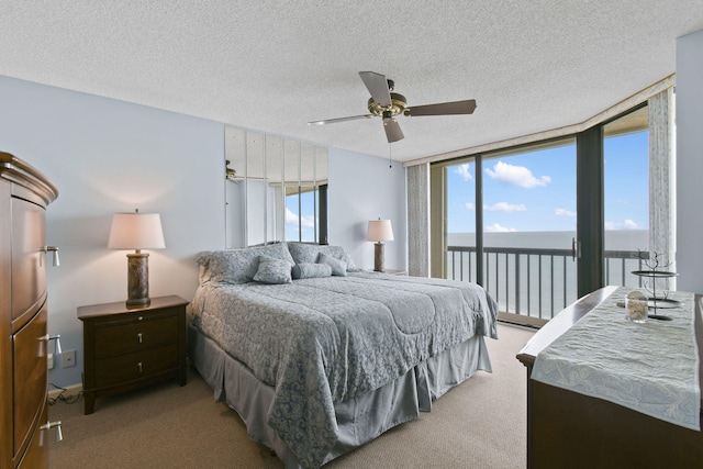 bedroom with a water view, carpet, access to outside, ceiling fan, and a textured ceiling