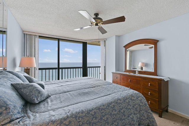 carpeted bedroom with ceiling fan, a water view, multiple windows, a textured ceiling, and access to outside