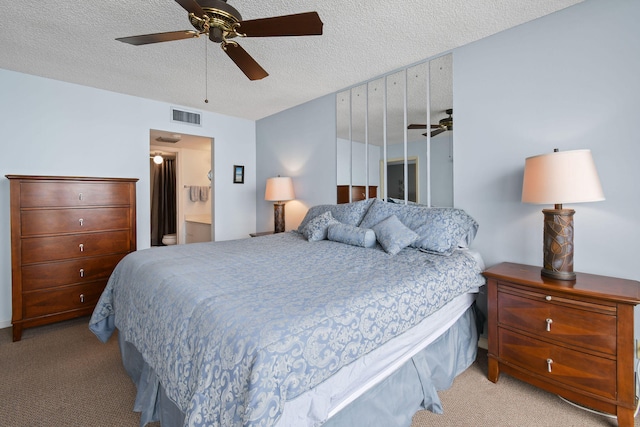 bedroom featuring light carpet, ensuite bathroom, ceiling fan, and a textured ceiling