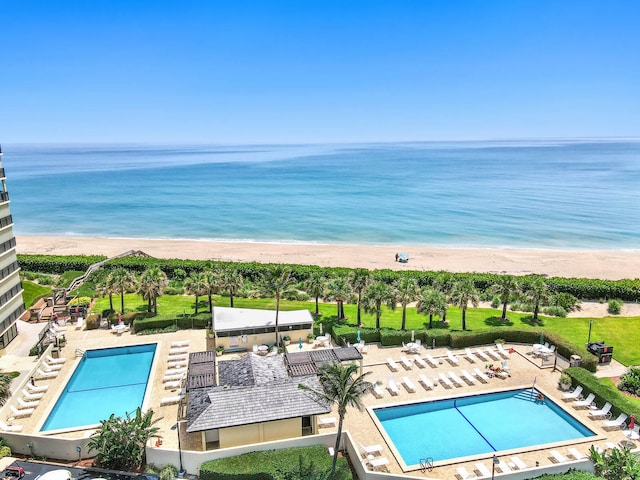 view of swimming pool featuring a beach view, a water view, and a patio