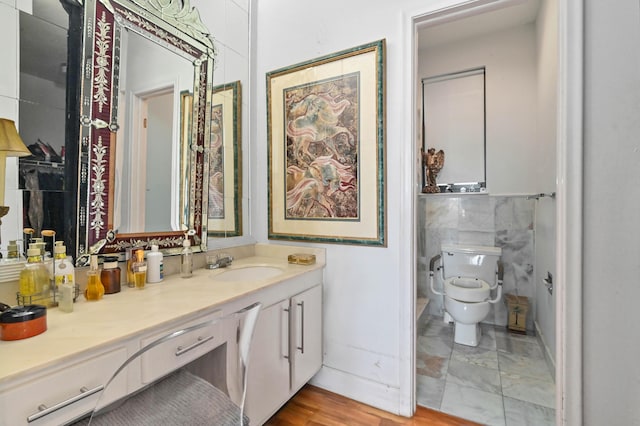 bathroom with toilet, vanity, and tile walls