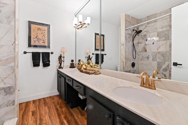 bathroom with double sink vanity, a chandelier, toilet, hardwood / wood-style flooring, and a tile shower