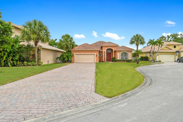 mediterranean / spanish-style house featuring decorative driveway, a tile roof, stucco siding, an attached garage, and a front yard