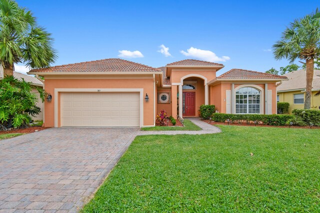 mediterranean / spanish home with a garage and a front lawn