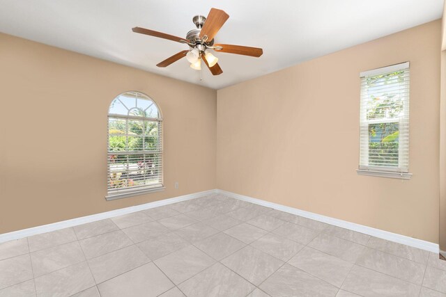 empty room featuring ceiling fan, a healthy amount of sunlight, and light tile floors