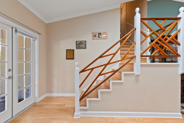 staircase with french doors, lofted ceiling, ornamental molding, and light wood-type flooring