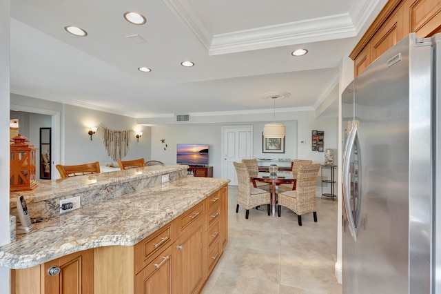 kitchen with stainless steel fridge, crown molding, decorative light fixtures, and light stone counters