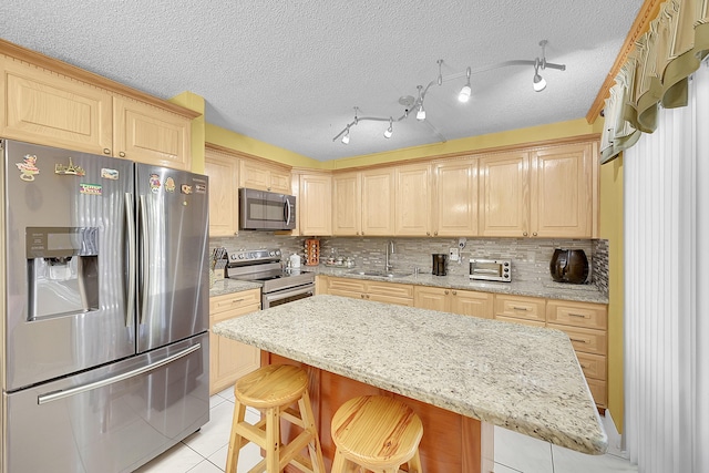 kitchen with a center island, a breakfast bar, stainless steel appliances, light tile patterned flooring, and a sink