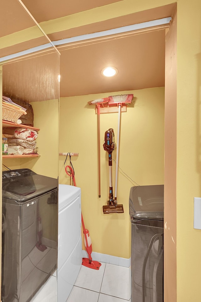 laundry room featuring washing machine and dryer, laundry area, baseboards, and light tile patterned floors