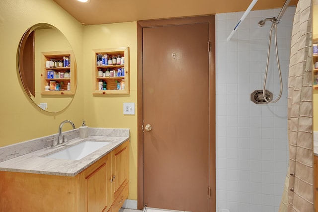 full bath featuring built in features, a tile shower, and vanity