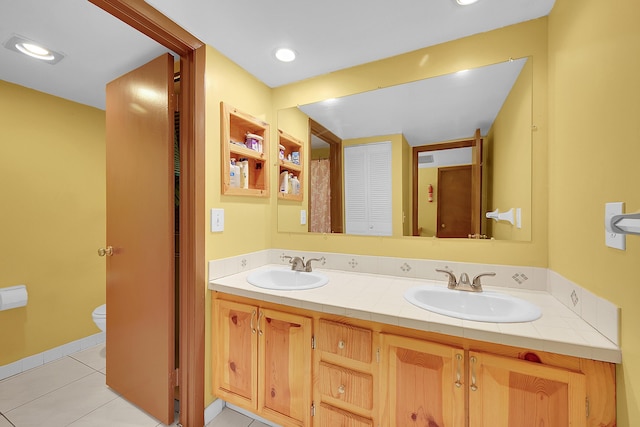 bathroom with double vanity, toilet, a sink, and tile patterned floors