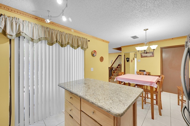 kitchen with a textured ceiling, hanging light fixtures, light tile patterned floors, and visible vents