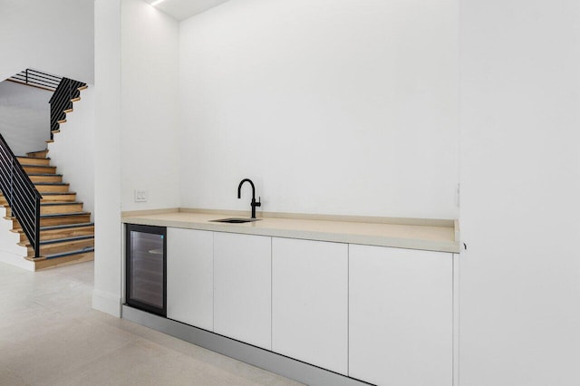 bar with wine cooler, sink, and white cabinets