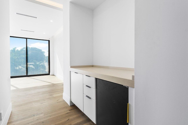 bar featuring floor to ceiling windows, light hardwood / wood-style floors, and white cabinets