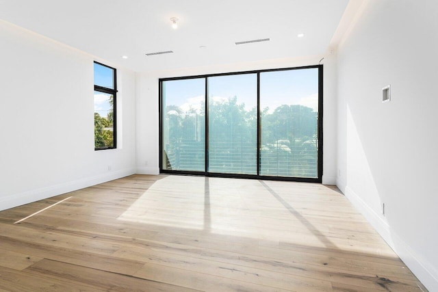 unfurnished room featuring floor to ceiling windows and light wood-type flooring