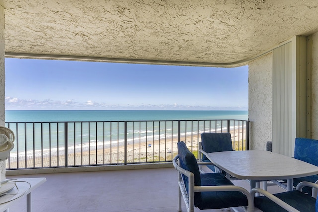 balcony featuring a view of the beach and a water view