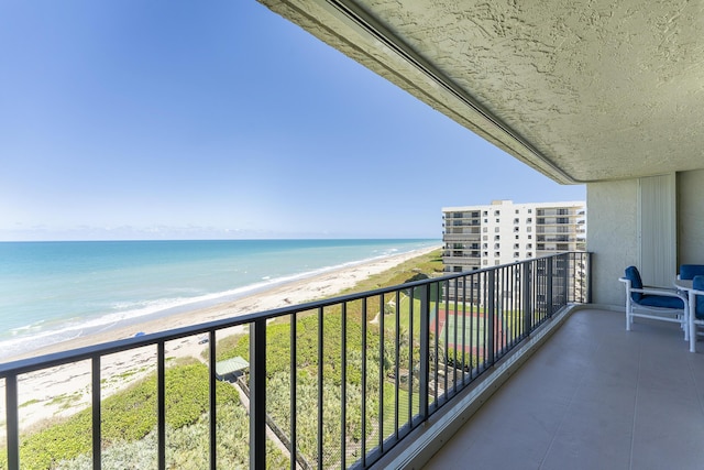 balcony featuring a view of the beach and a water view