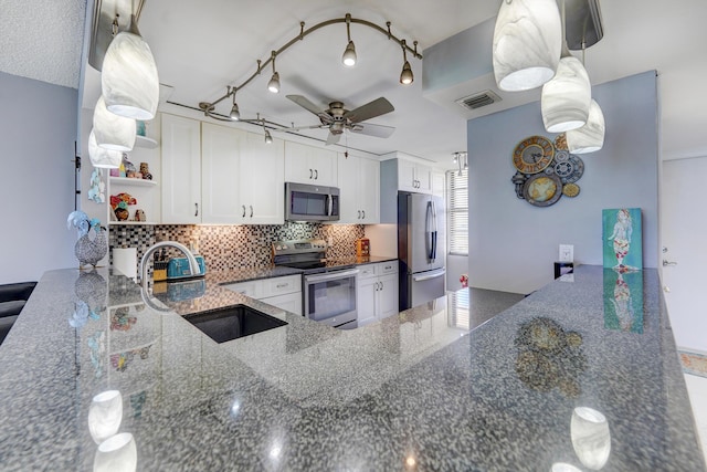 kitchen with white cabinets, sink, stainless steel appliances, and dark stone counters