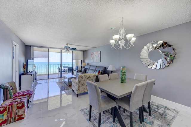 dining room with ceiling fan with notable chandelier, a textured ceiling, and a wall of windows