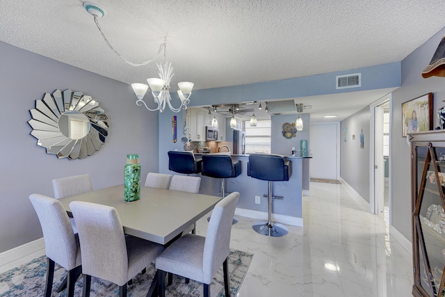 dining room with ceiling fan with notable chandelier and a textured ceiling