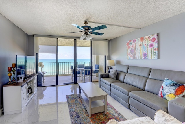 living room with ceiling fan, expansive windows, and a textured ceiling