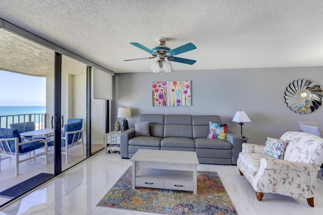 living room with a textured ceiling, a water view, floor to ceiling windows, and ceiling fan