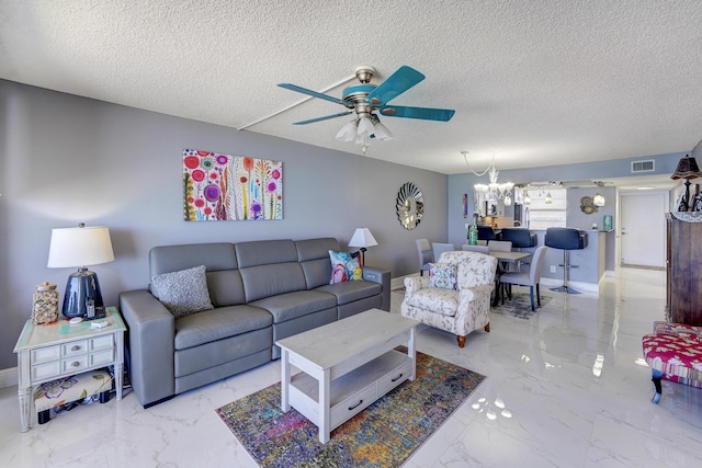 living room featuring ceiling fan with notable chandelier and a textured ceiling