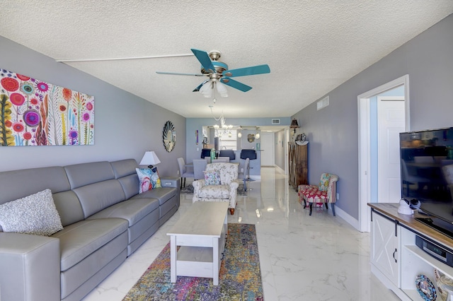 living room featuring ceiling fan with notable chandelier and a textured ceiling