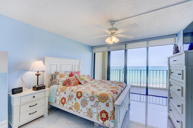 bedroom with access to exterior, ceiling fan, a textured ceiling, and a wall of windows