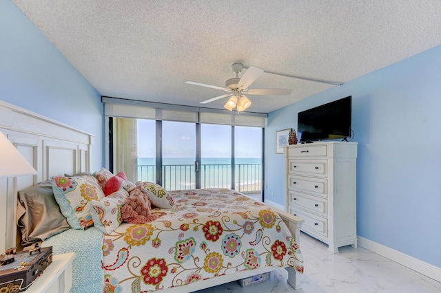 bedroom featuring ceiling fan, access to exterior, a wall of windows, and a textured ceiling