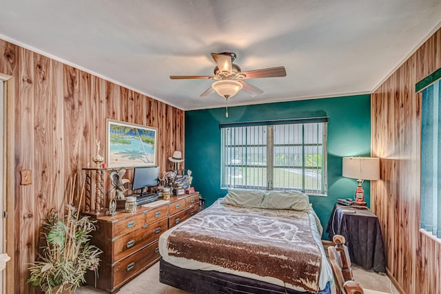 carpeted bedroom featuring crown molding, ceiling fan, and wood walls