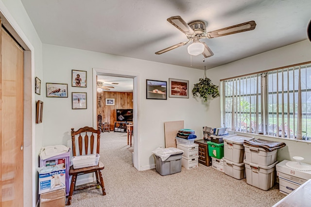 interior space with carpet floors, ceiling fan, and wood walls