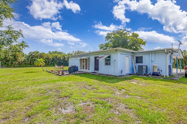 rear view of house featuring a yard, central AC unit, and a patio area