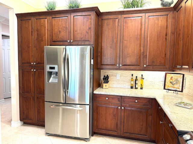 kitchen featuring backsplash, light stone countertops, stainless steel fridge with ice dispenser, and light tile floors