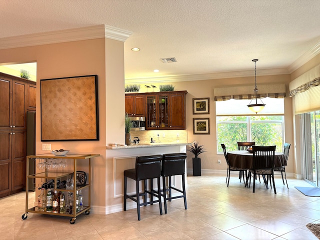 kitchen featuring decorative light fixtures, a textured ceiling, tasteful backsplash, and light tile floors