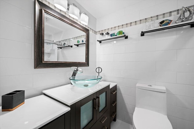 bathroom with toilet, vanity, and tile walls