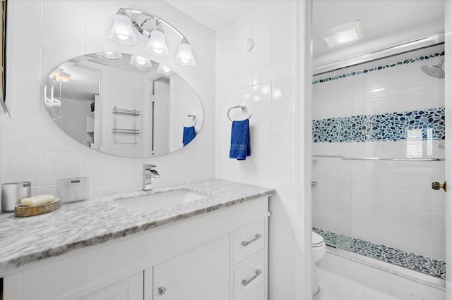 bathroom featuring tiled shower, tile flooring, toilet, tile walls, and oversized vanity