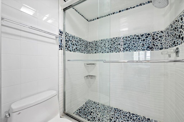 bathroom featuring tile walls, a shower with door, and toilet