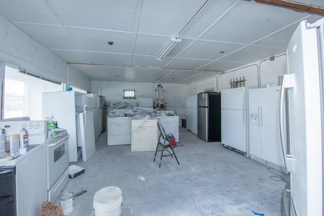 kitchen with white cabinets, white appliances, and washing machine and clothes dryer