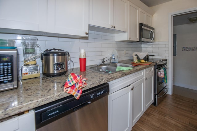 kitchen with stainless steel appliances, sink, white cabinetry, and tasteful backsplash