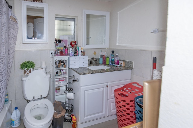 bathroom with vanity with extensive cabinet space, tile walls, and toilet