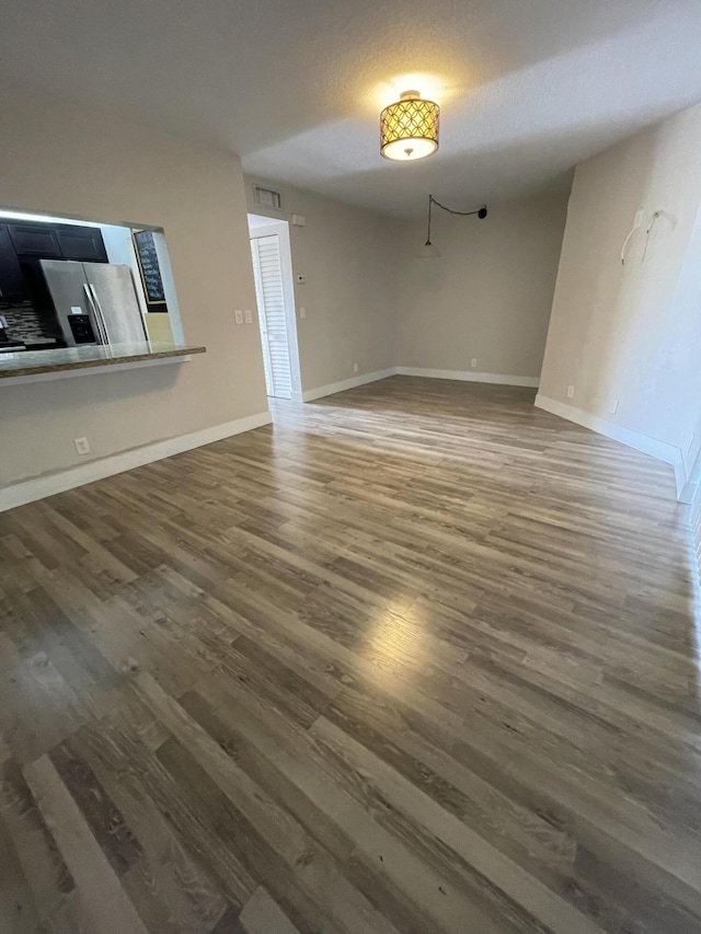 unfurnished living room featuring dark wood-type flooring and a textured ceiling