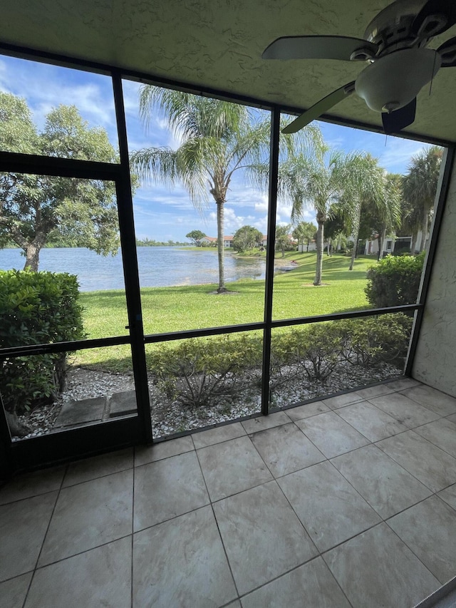 unfurnished sunroom featuring a water view and ceiling fan