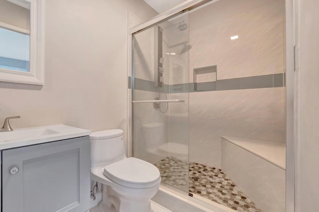 bathroom featuring a shower with shower door, vanity, and toilet