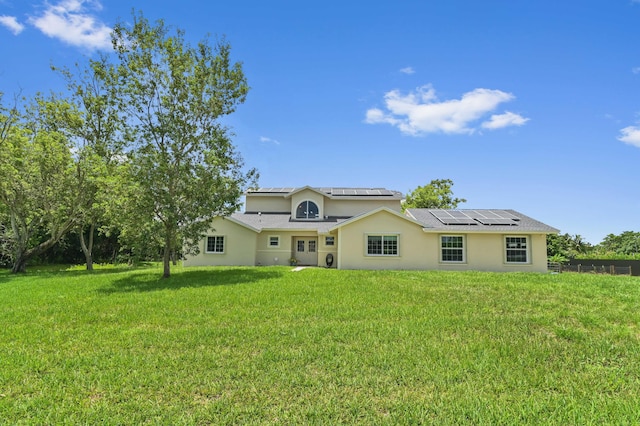 rear view of house with solar panels and a yard